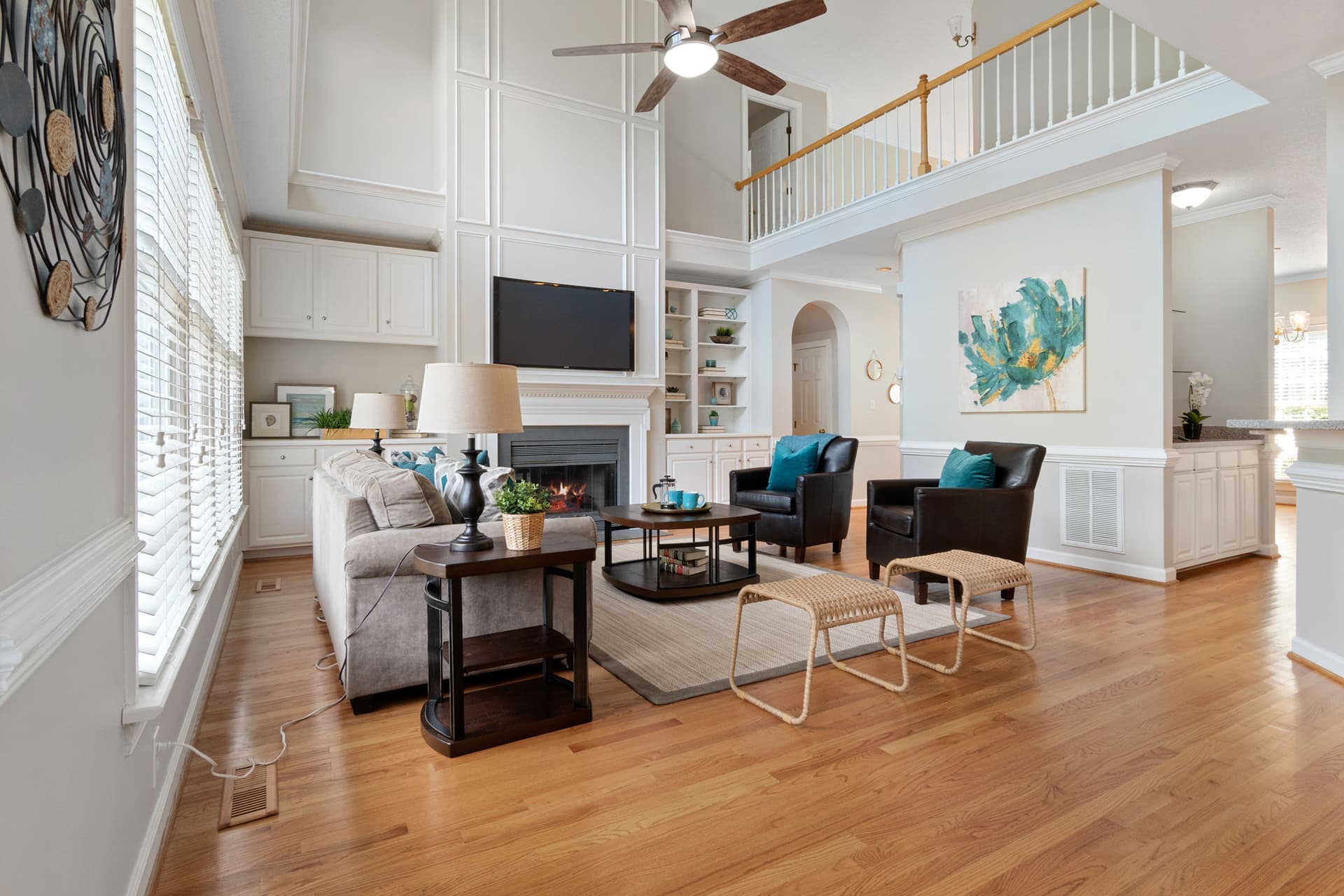 A ceiling fan turning slowly in a bright room with high ceilings and afternoon light on the wall